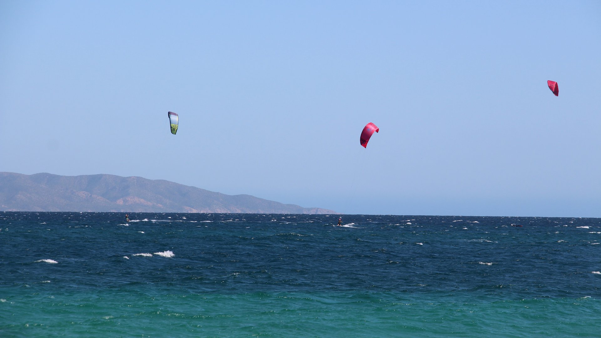 View into the green blue ocean of La Ventana with 3 kitesurfers