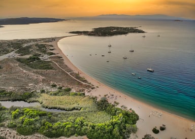 Porto Pollo Kiteboarding in Italy view from above countryside to the island and beach in the sunset with very calm sea and some boats laying at anchor in the water