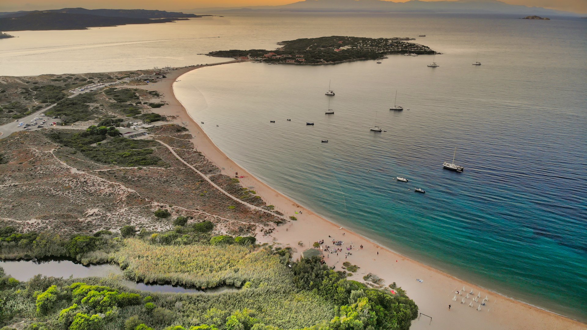 Porto Pollo Kiteboarding in Italy view from above countryside to the island and beach in the sunset with very calm sea and some boats laying at anchor in the water