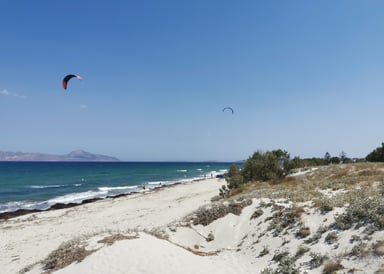 Mastichari Beach Kitesurfing in Kos natural hilly beach with fine wihte sand and 2 kitesurfers in the background on the windy sea