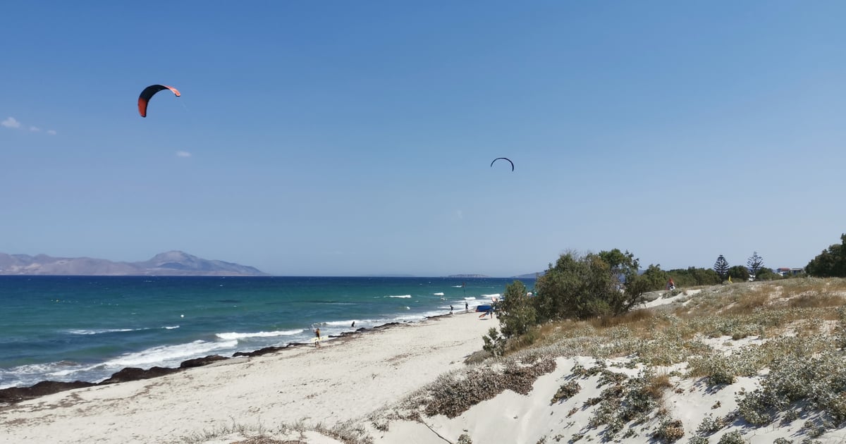 Mastichari Beach Kitesurfing in Kos natural hilly beach with fine wihte sand and 2 kitesurfers in the background on the windy sea