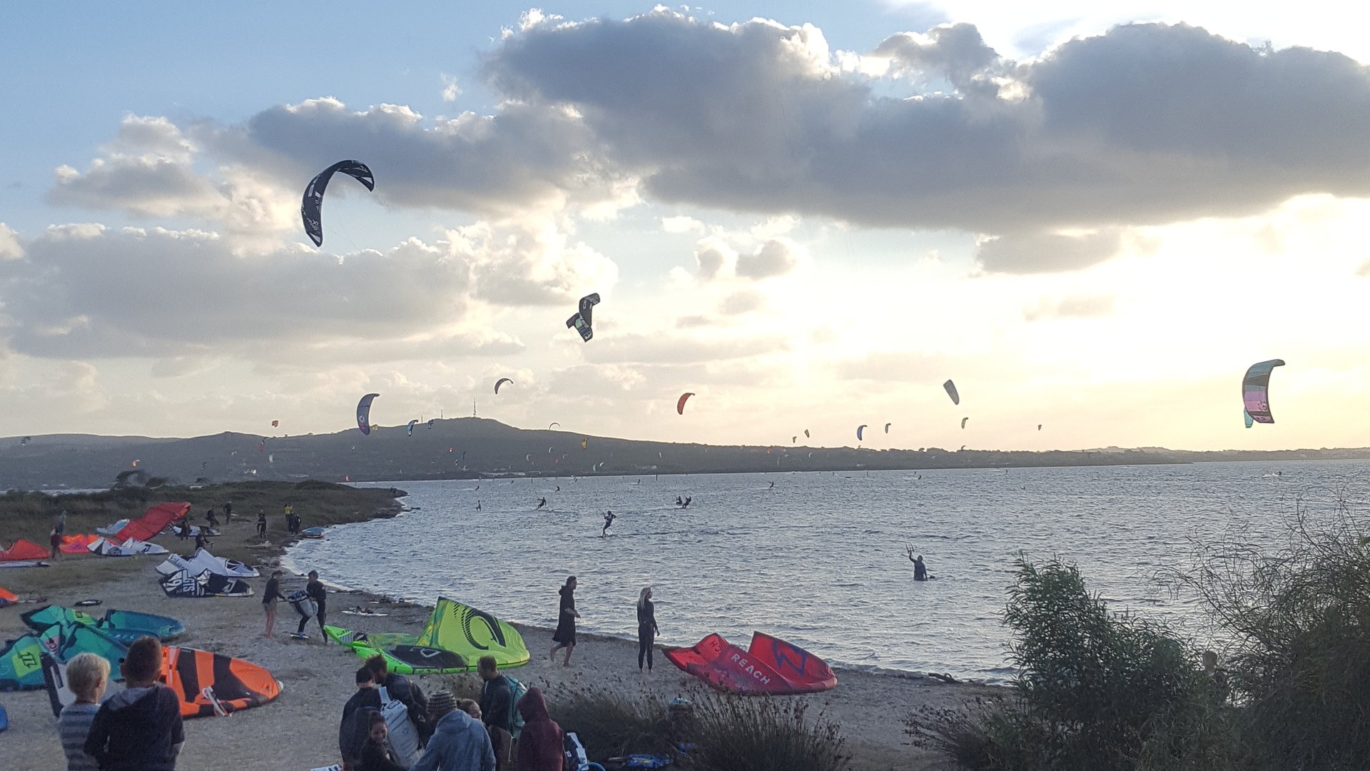 Punta Trettu Kitesurfing in Sardinia view close from the beach with a lot of kitesurfers preparing the kite or already about 20 on the water