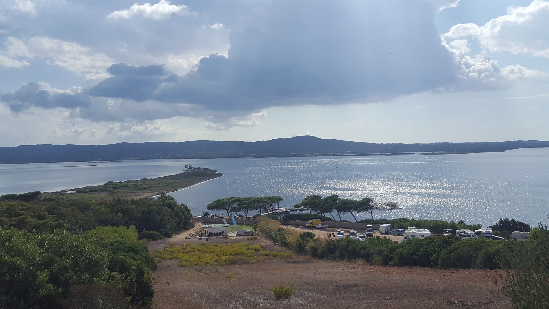 Punta Trettu Kitesurfing in Sardinia view from a hill to the sea with sunbeans shining through the clouds