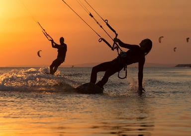 Can Pastilla Kitesurfing in Mallorca two kitesurfers in cheesy sundown with red light and more kitesurfers in the background