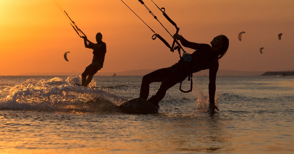 Can Pastilla Kitesurfing in Mallorca two kitesurfers in cheesy sundown with red light and more kitesurfers in the background
