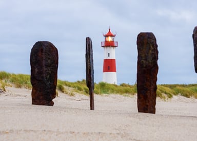 List Kiteboarding in Sylt old wood sticked in the sand with lighthouse in background