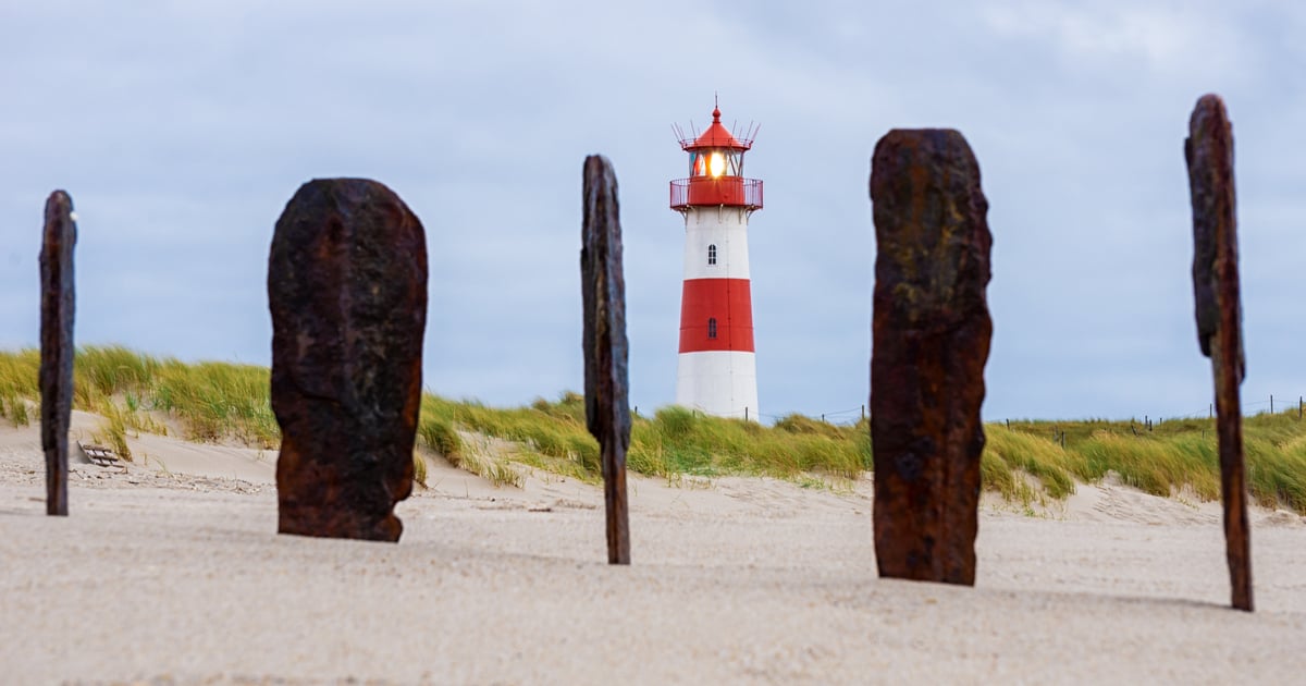 List Kiteboarding in Sylt old wood sticked in the sand with lighthouse in background