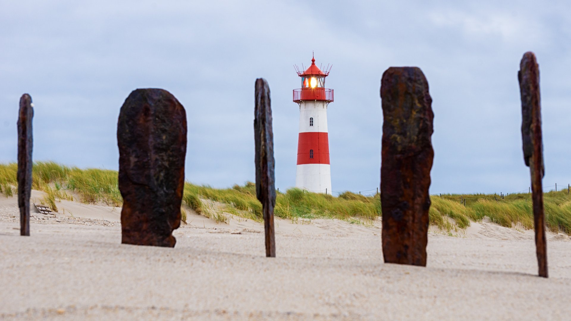 List Kiteboarding in Sylt old wood sticked in the sand with lighthouse in background