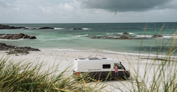 Campervan standing at Tiree beach in Scottland with Kitesurfers in the background