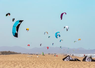 Sant Pere Pescador Kitesurfing in Costa Brava with a view sideshore with 20 colourful kites in the sky and laying at the yellow sandy beach