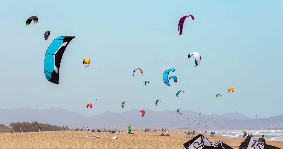 Sant Pere Pescador Kitesurfing in Costa Brava with a view sideshore with 20 colourful kites in the sky and laying at the yellow sandy beach