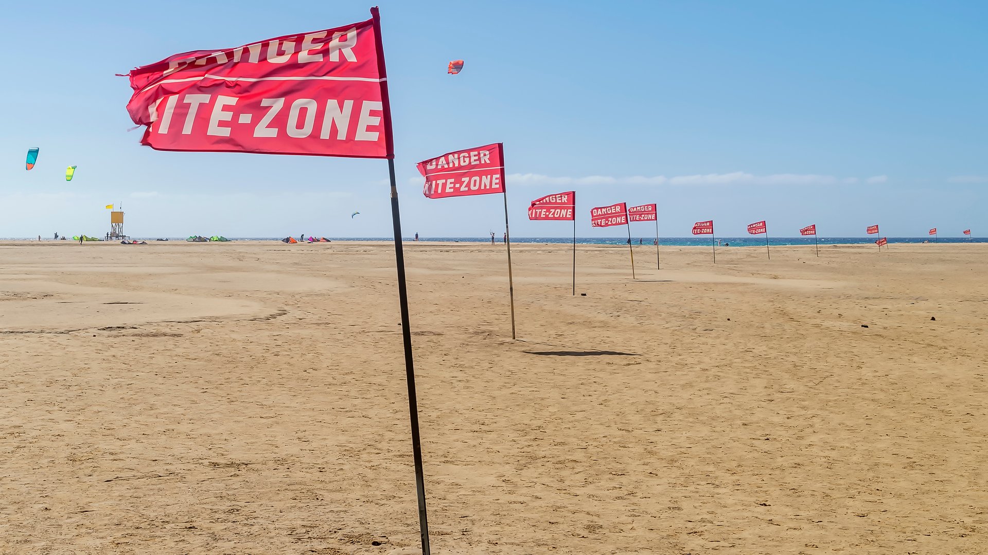 Flag Beach Kiteboarding in Fuerteventura nice shot with a dozen of red kite-zone flags in a row blown in the wind