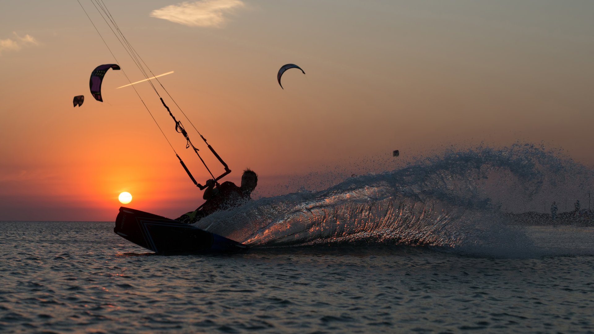 Kitesurfing iconic shot of a kiter making a turn in the sunset with at red sky