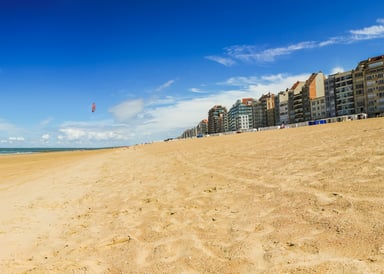 Zeebrugge Kitesurfing Belgium with a Kitesurfer in the background and houses on the sunny beach