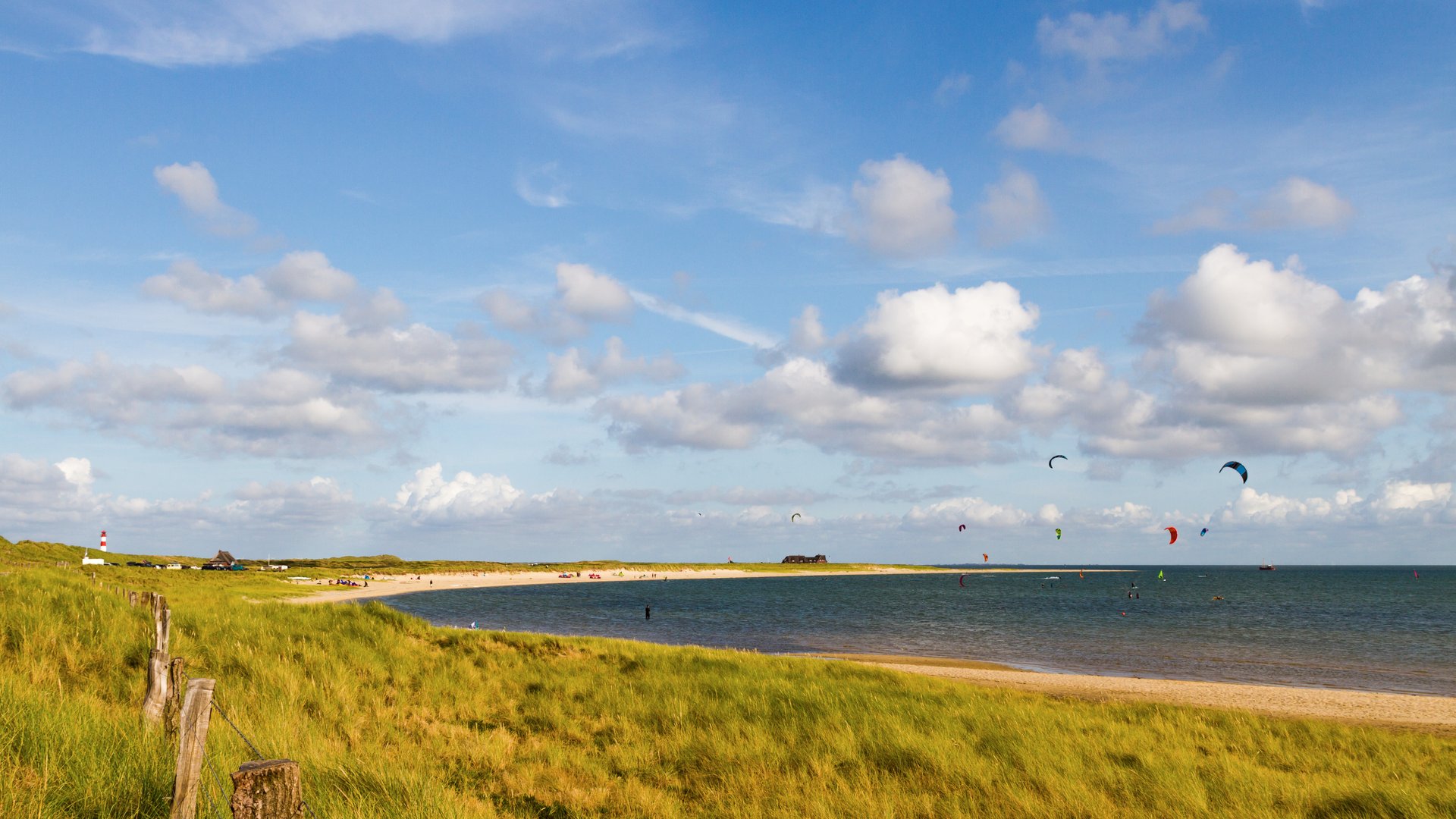 Westerland Kiteboarding Spot in Sylt with a few Kitesurfers out on the sea visible from a hill from far at the beachline
