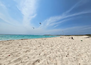 Empty Kitebeach with white sand and kitesurfers riding at Boca Grandi Aruba