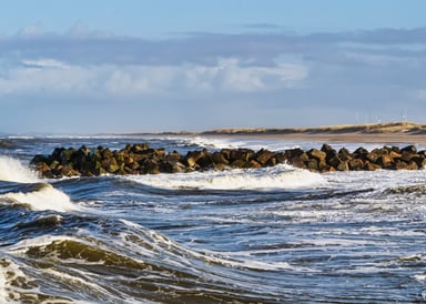 Thorsminde Kitesurfing in Denmark with gusty sea, sandy beach and windmills in the background