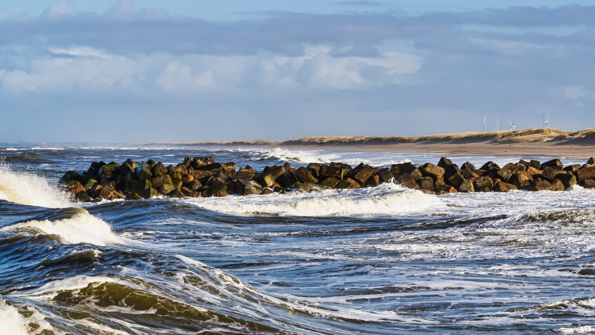 Thorsminde Kitesurfing in Denmark with gusty sea, sandy beach and windmills in the background
