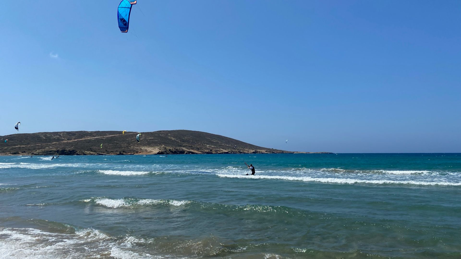 Prasonisi Beach Kitesurfing in Greeece two kiters in the water with low wind and a flat hill in the background
