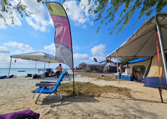 Sandy beach with colorful tents and lounge chairs overlooking the ocean on a sunny day.