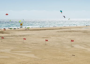 Sotavento Kitesurfing beach in Fuerteventura image from far with view from the large beach to the sea with sunny weather and about 10 kitesurfers in the sky