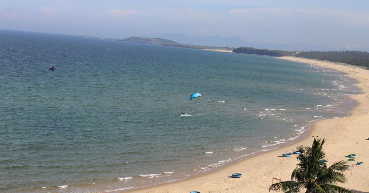 Man holding up a blue kite in the air
