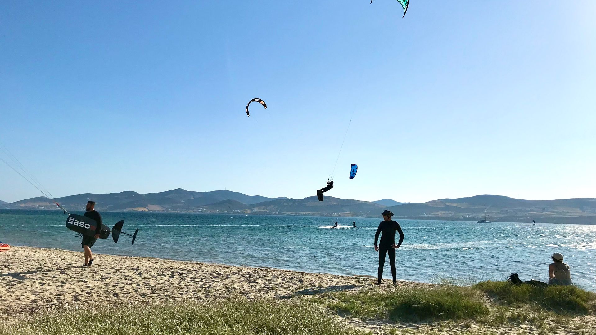 Paralia Pounta Kitesurfing in Kos with a kiter jumping high and a foil kitesurfer getting ready 