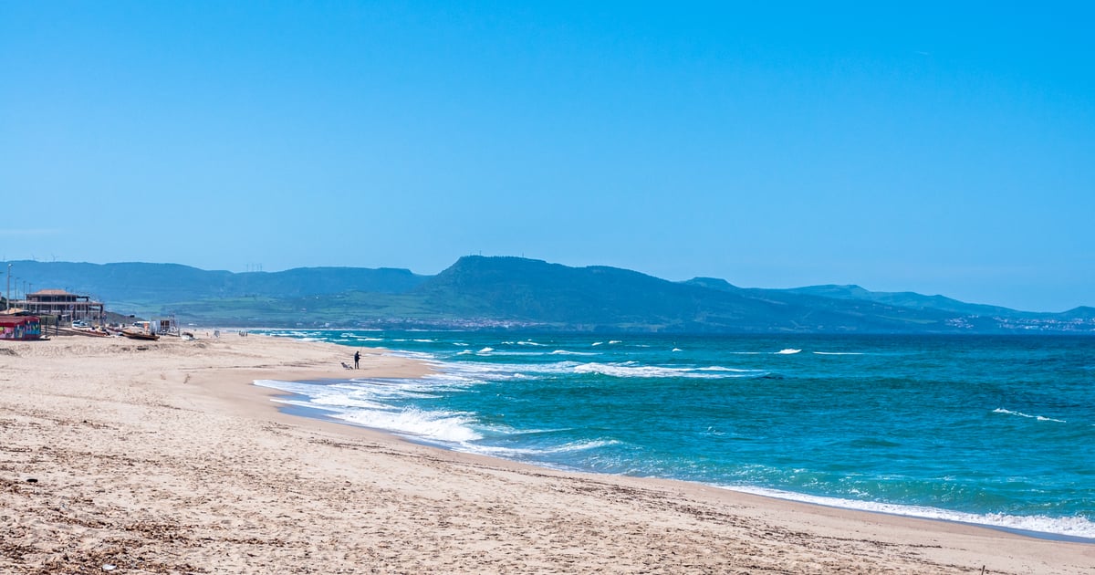 Badesi Kitesurfing in Sardinia image of a lonely sandy beach with blue sky and Mountains in the background