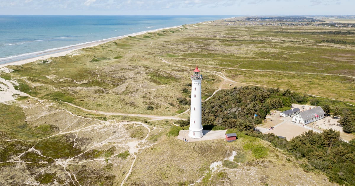 Hvide Sand Kiteboarding at Denmark coastline with lighthouse in front, green open fields and blue sea in the background