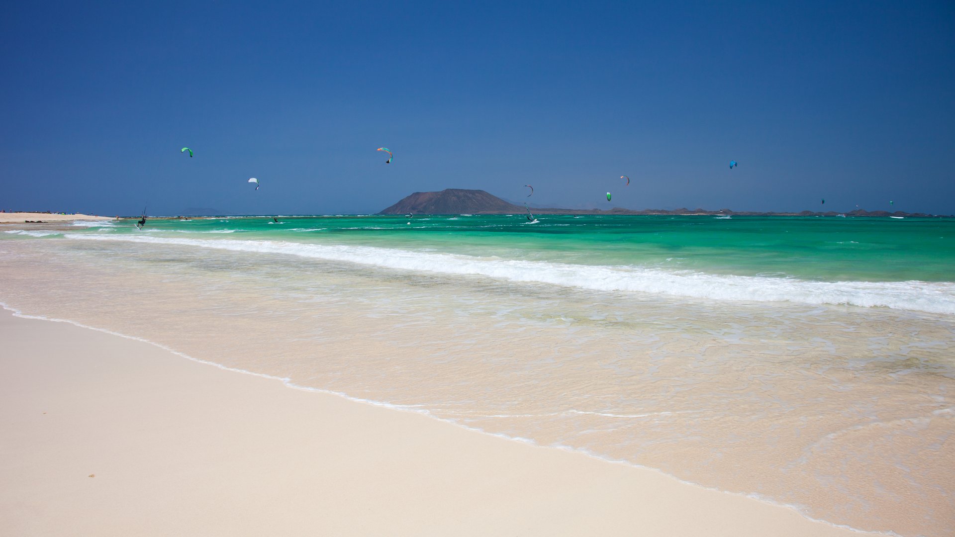 Flag Beach Kitebsurfing in Fuerteventura white sand and turquoise water and a picturesque hill in the background looking like an island