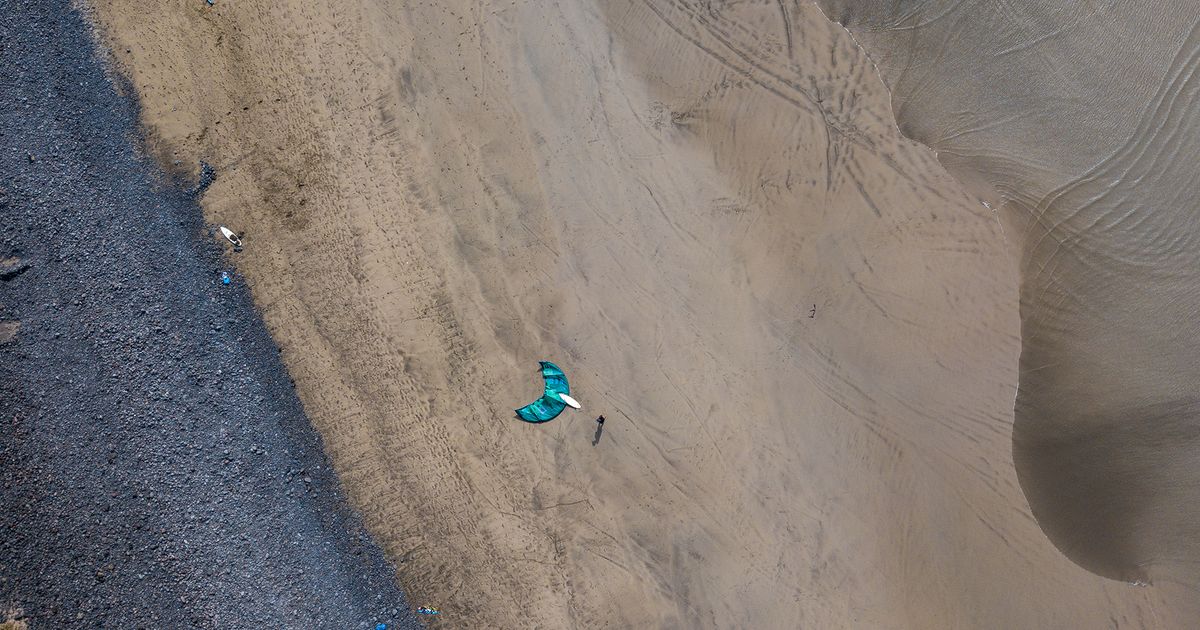 Famara Kiteboarding in Lanzarote beautiful view from above an the beach and blue ocean in the left corner with one kitesurfer preparing his or her kite