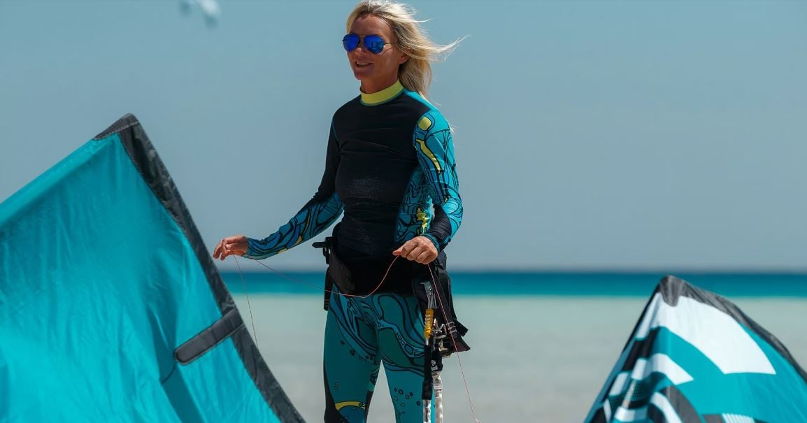 Sigri Kitesurfing in Lesbos Greece image of a closeup shot of a woman holding her turqoise kite smiling on the beach