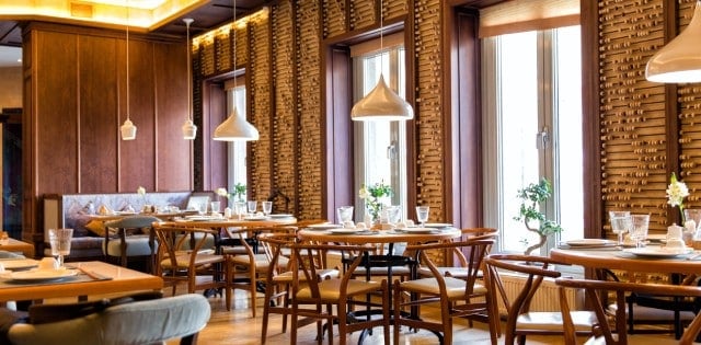 An upscale restaurant with Asian-inspired décor and architecture, lit by natural light and overhead lighting.