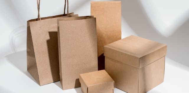 Closeup of various shapes and sizes of kraft paper and cardboard product packaging in front of a white background.