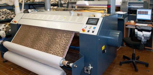 A large printer uses a textile to execute its next task. The machine has a digital screen above the physical buttons.