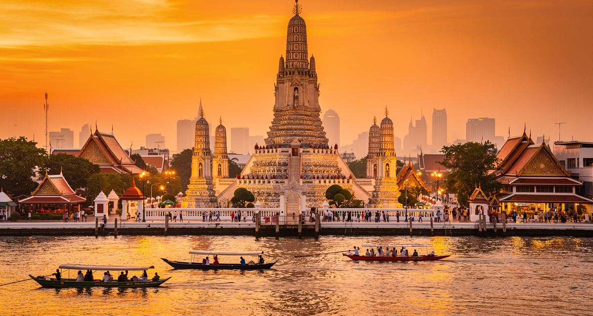 Wat Arun temple on the Chao Phraya river in Bangkok at golden hour with ornate spires and traditional Thai architecture, representing Thailand and the +66 international dialing code