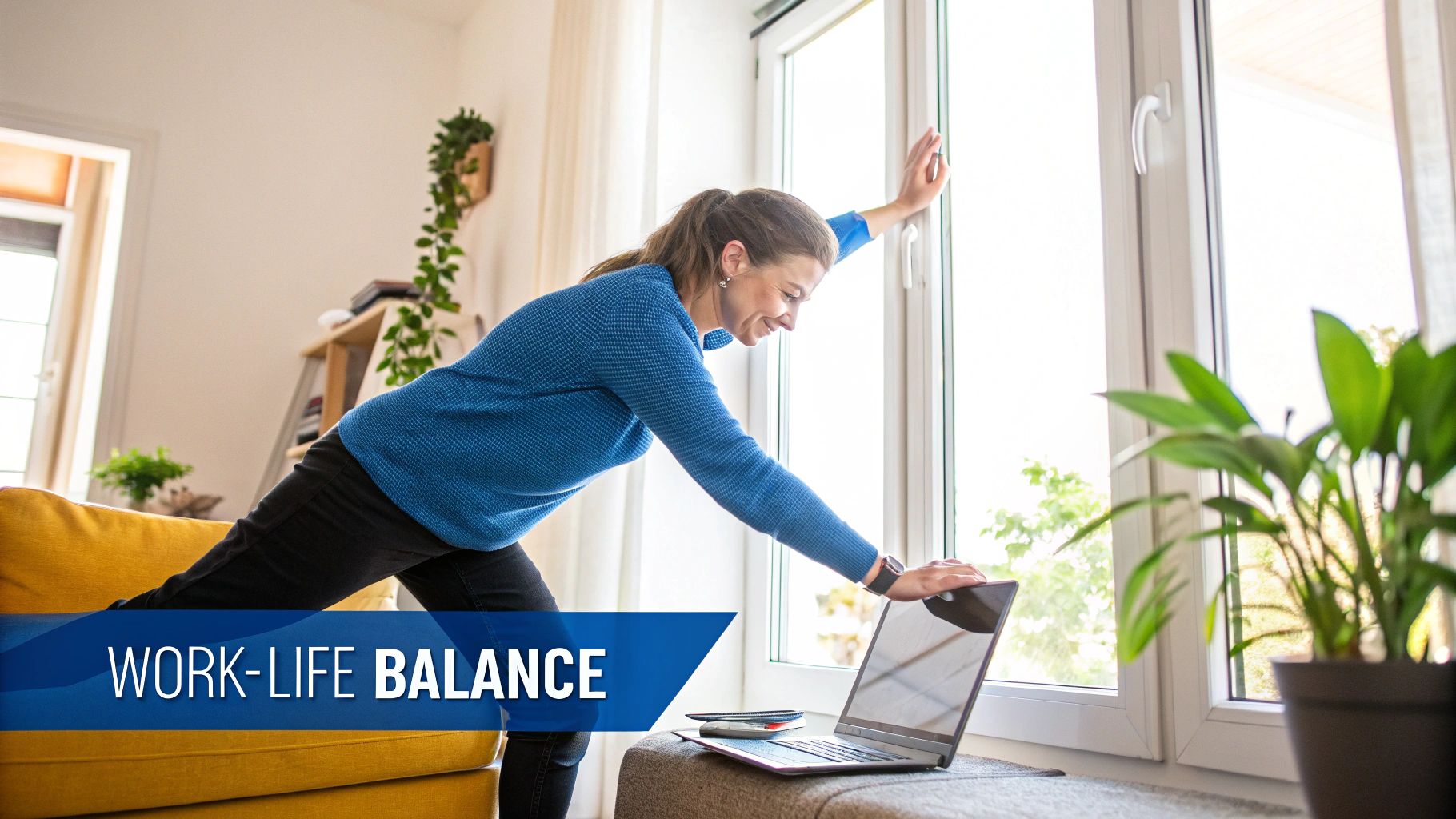 Une femme souriante en pull bleu s'étire près d'une grande fenêtre, faisant une pause de son ordinateur portable.