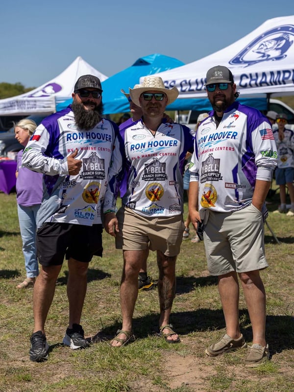 Three anglers posing in tournament jerseys at an event