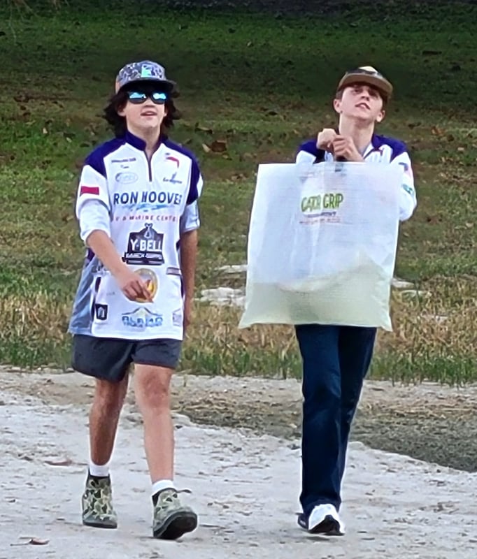 Two youth anglers walking with a fish bag at a tournament