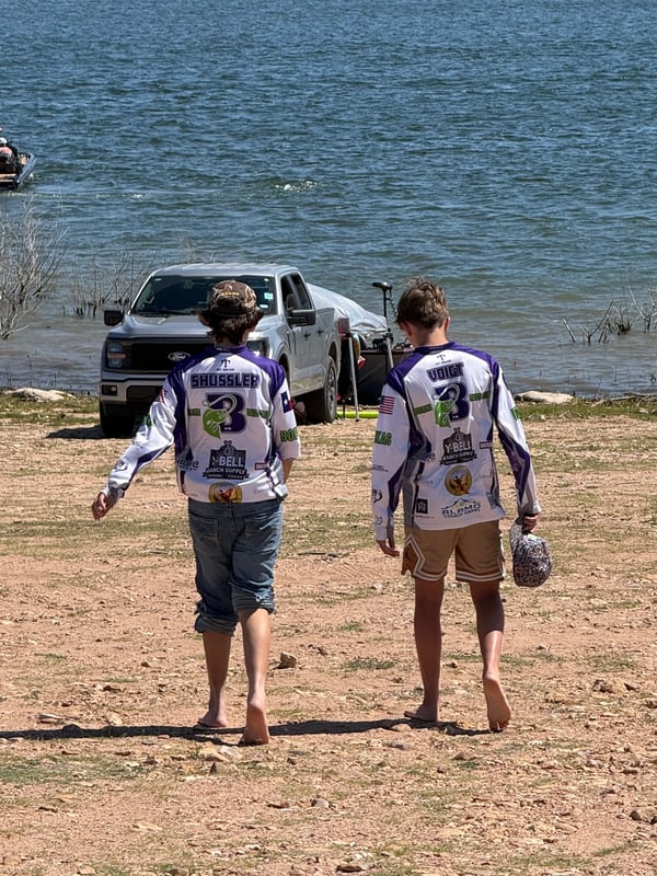 Two young anglers walking towards water during a fishing tournament