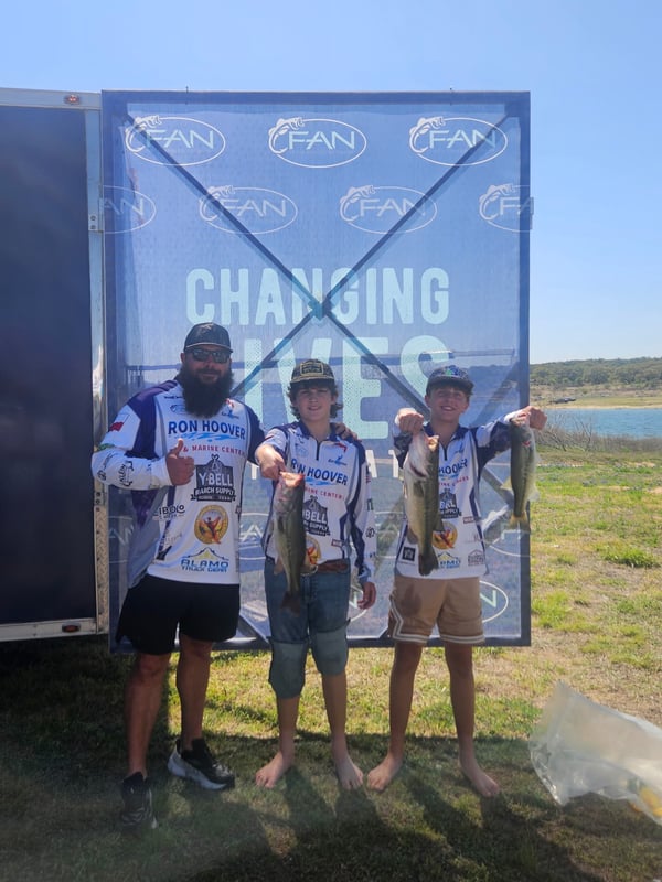 Three anglers proudly displaying their catches at a fishing tournament