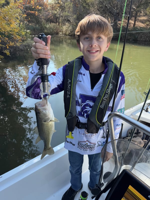 A young angler proudly holding a bass fish during a tournament.