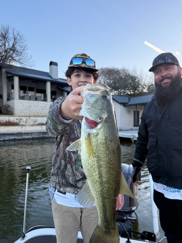 Young angler proudly displaying a large bass catch during a fishing tournament.