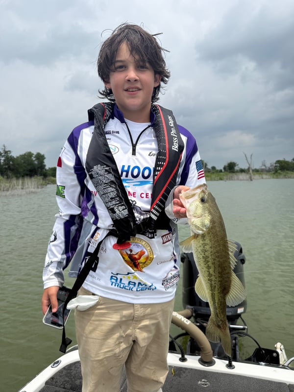 Youth angler holding a large bass during a fishing tournament.