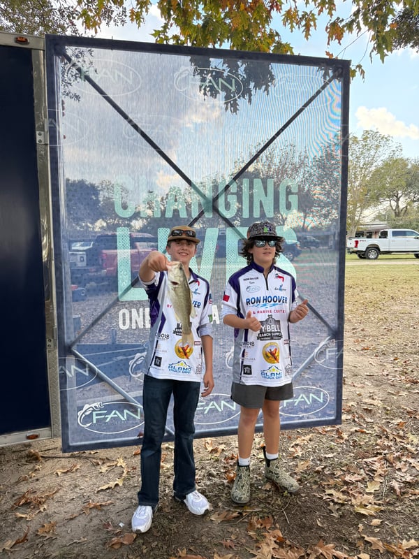 Two young anglers display their catch at a fishing tournament.