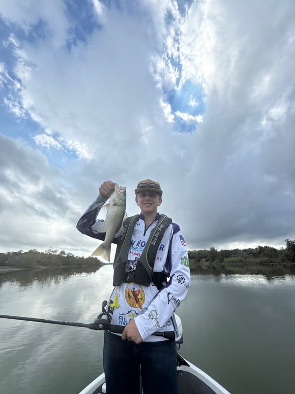 A young angler proudly holds a bass while fishing