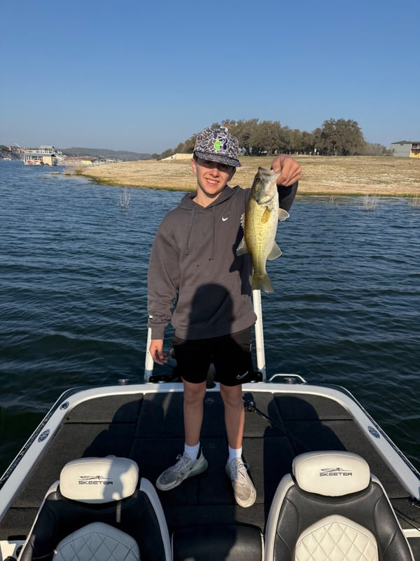 Young angler showing off a caught bass on a boat
