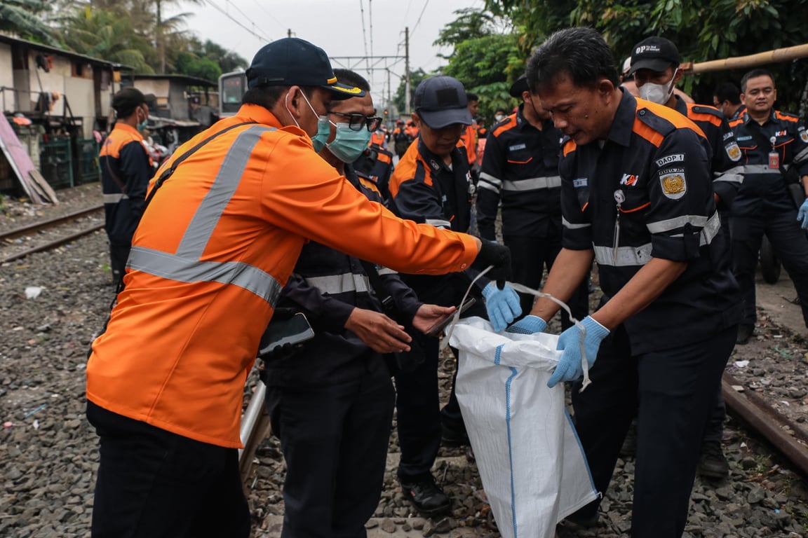 Petugas KAI Daop 1 Jakarta memungut sampah yang berada di sekitar jalur kereta api.