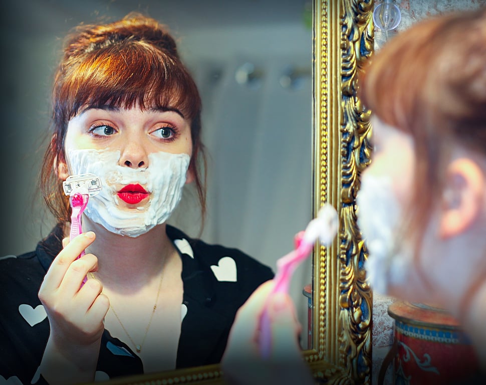 Ilustrasi perempuan dengan kumis yang sedang mencukur kumis dan jenggot. Image by John Ondreasz from Pixabay.