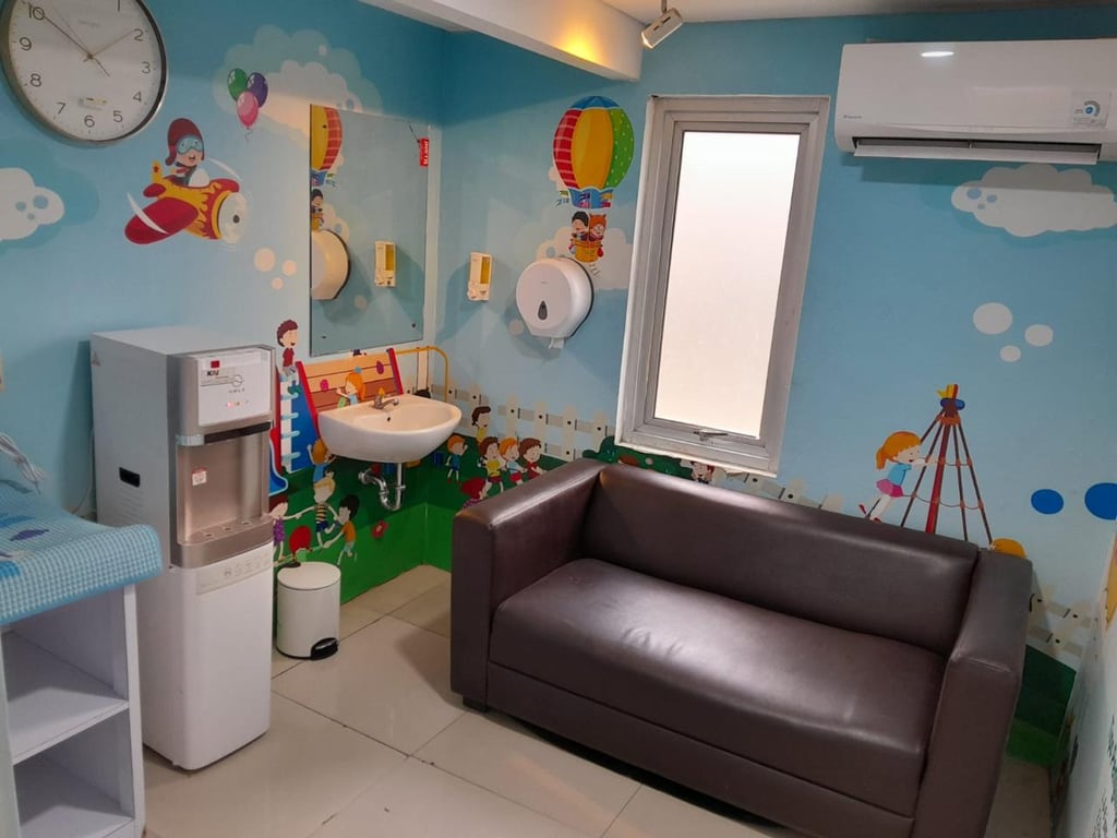 Suasana interior nursery room ber-AC dan dilengkapi dengan sofa, washtafel, dispenser, dan lainnya